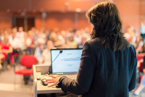 Woman presenting at a conference in front of an audience