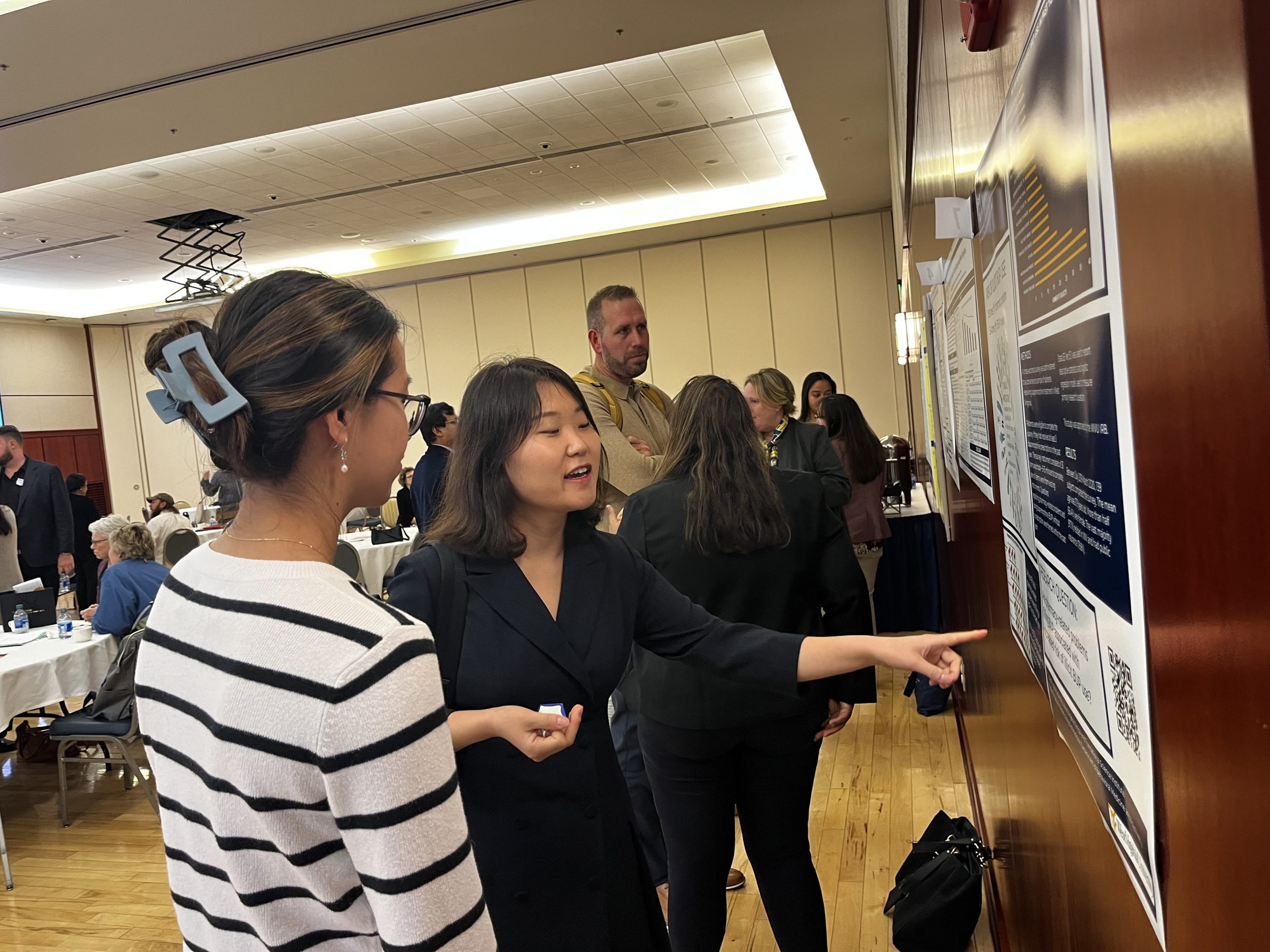 Dr Kang pointing at her poster and talking to an attendee