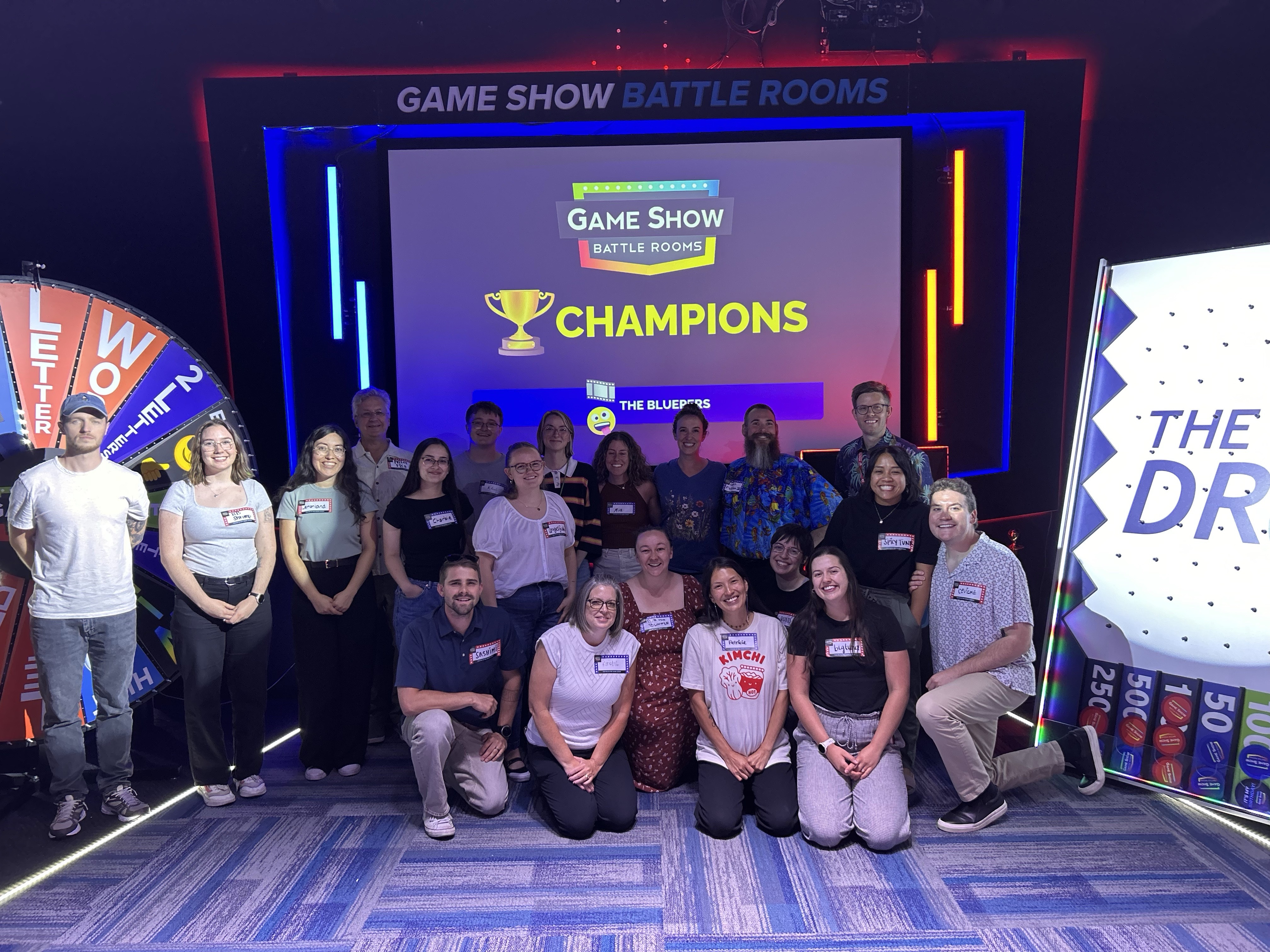 GIN team standing in front of Game Show Battle Rooms sign